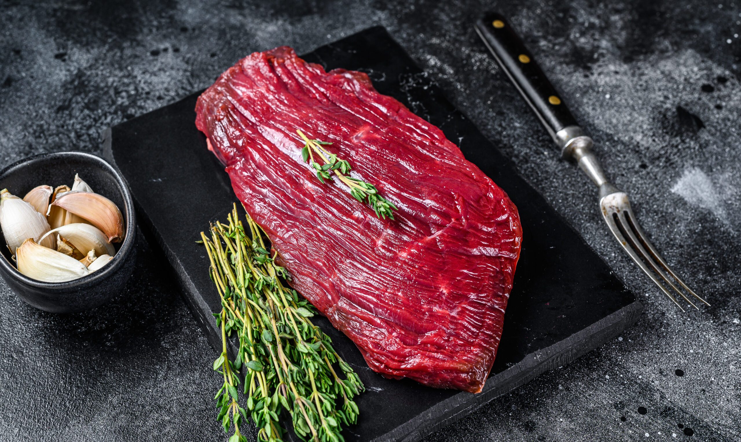 Venison raw steak from wild meat. Black background. Top view.